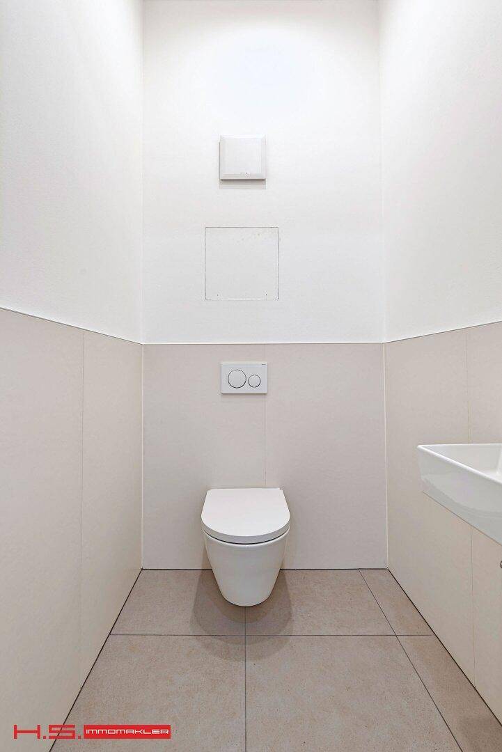Modernes Gäste-WC mit wandhängender Toilette und kleinem Waschbecken.