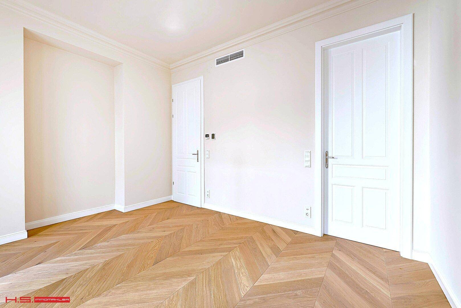Helles Zimmer mit Fischgrätparkett und hohen Türen, ideal als Schlaf- oder Arbeitszimmer.