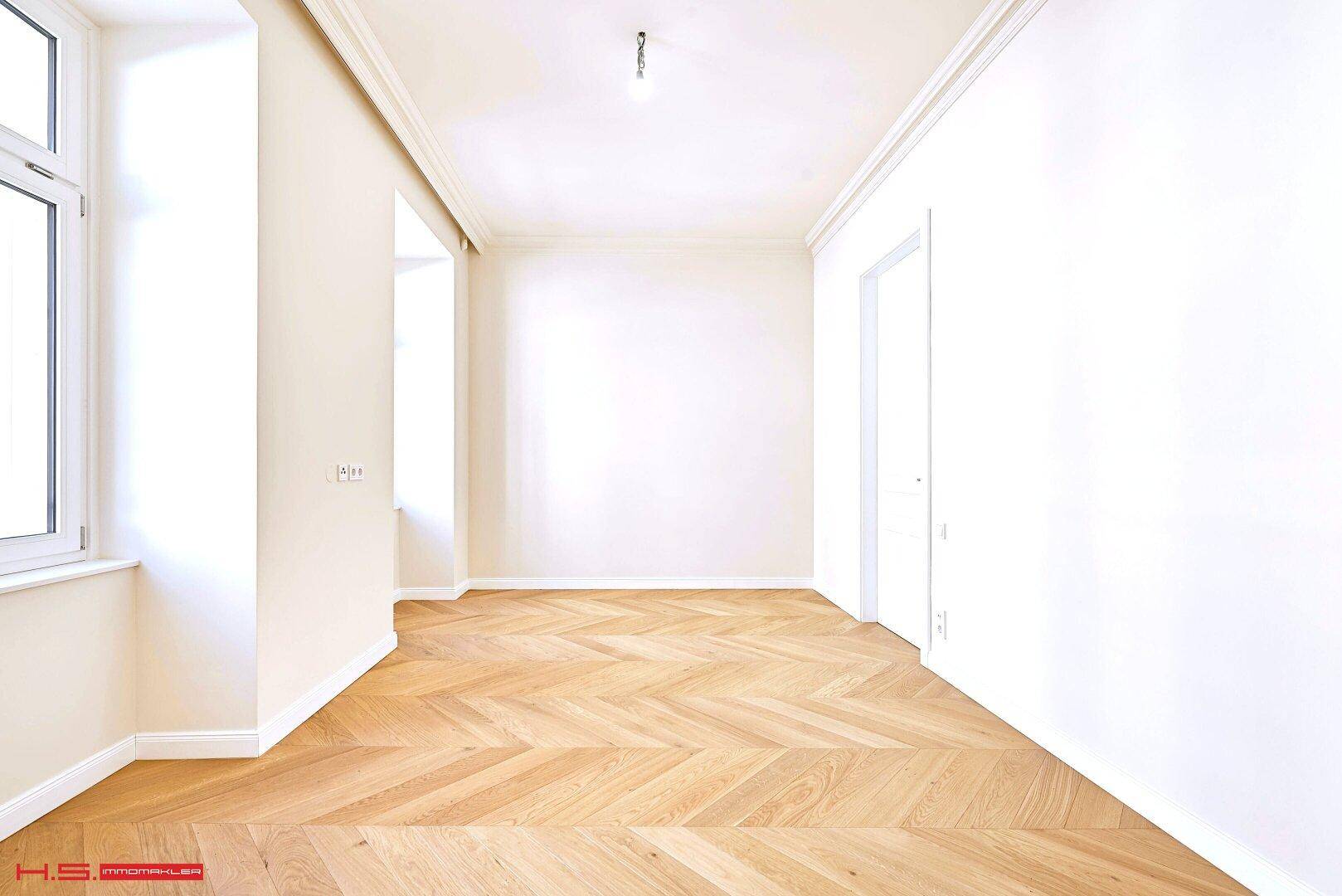 Heller Raum mit Fischgrätparkett und großem Fenster, bietet viel natürliches Licht.