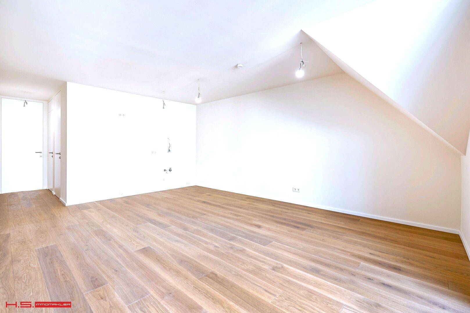 Geräumiger, heller Raum mit Holzboden und weißen Wänden, ideal für individuelle Gestaltung.