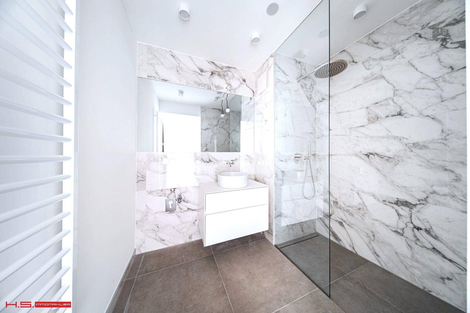 Modernes Badezimmer mit Marmorfliesen, begehbarer Dusche und elegantem Waschtisch.