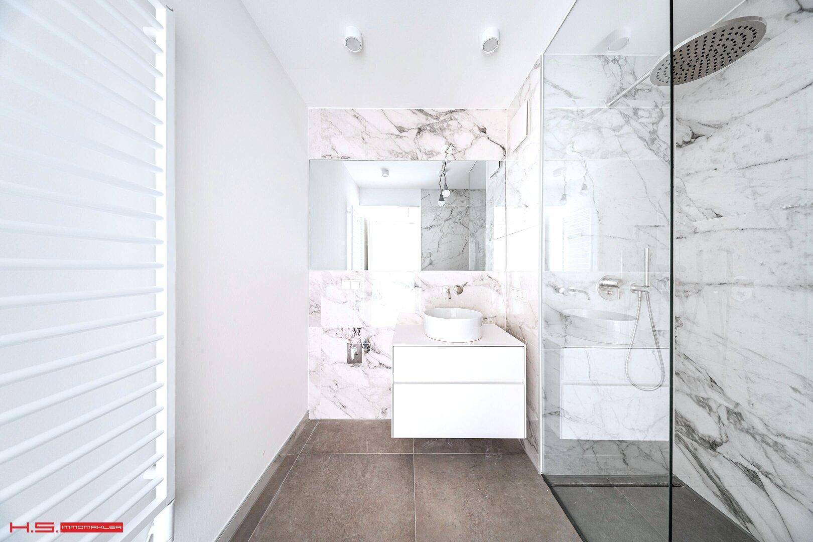 Elegantes Badezimmer mit Marmorfliesen, begehbarer Dusche und modernem Waschtisch.