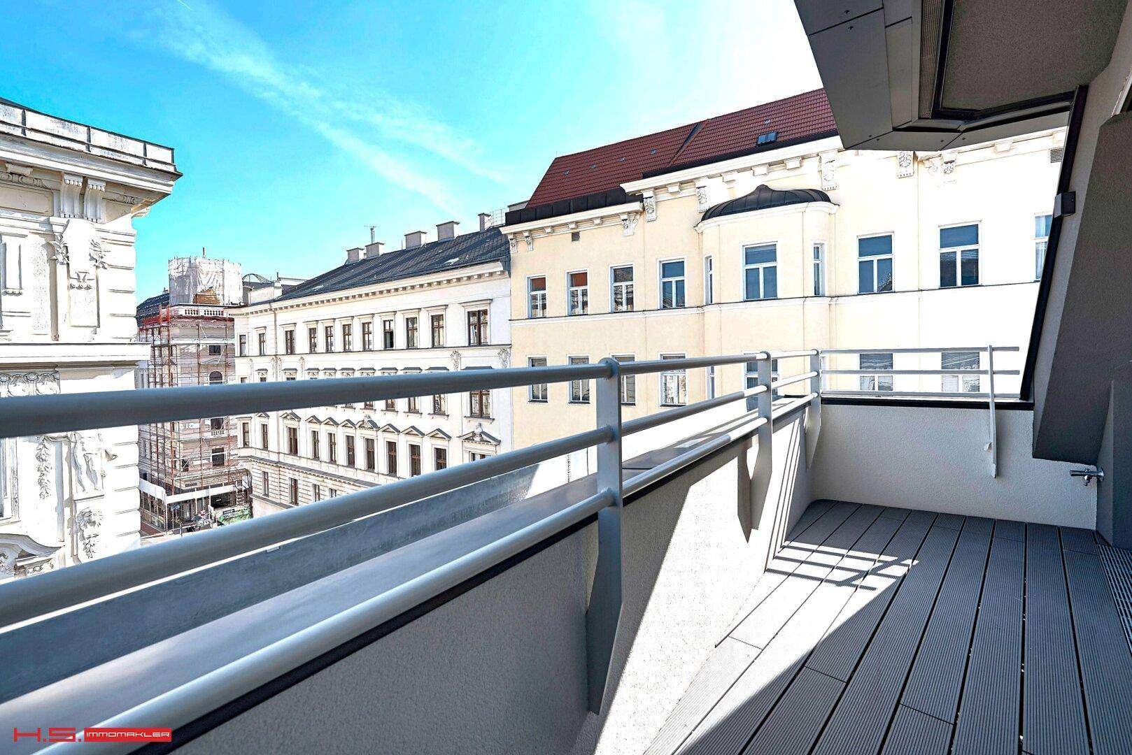 Geräumiger Balkon mit modernem Bodenbelag und Blick auf die umliegenden Stadtgebäude.