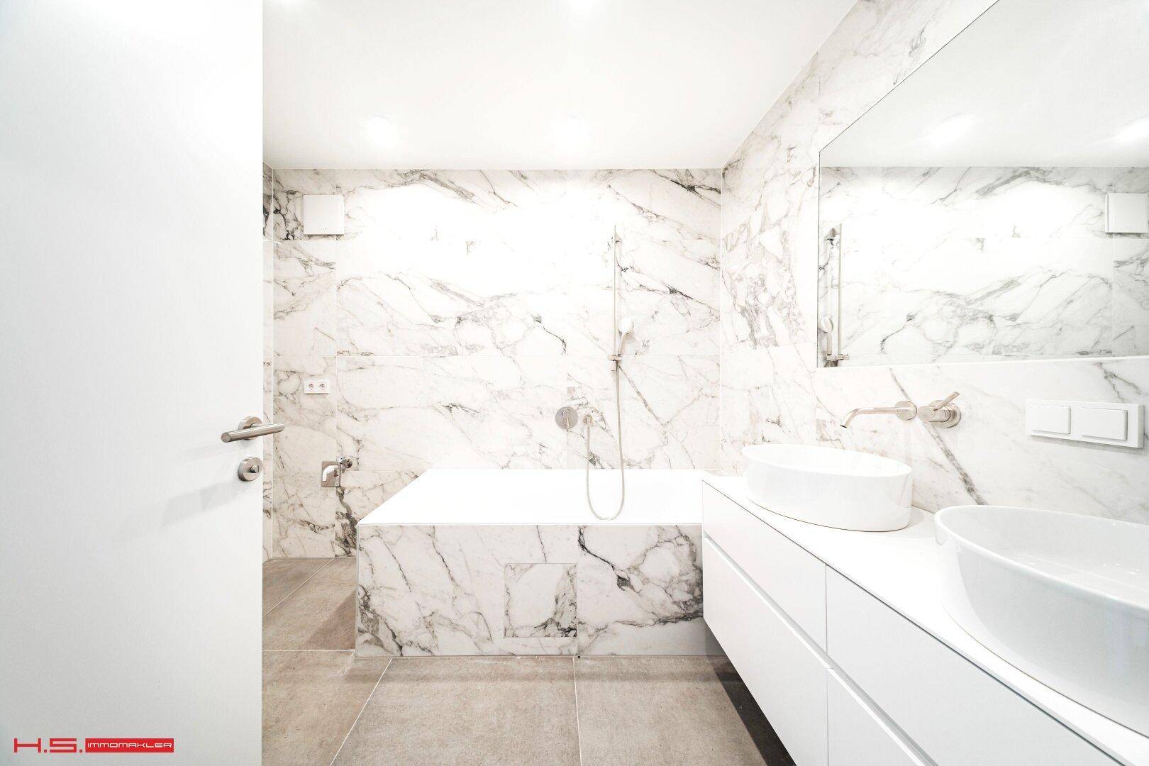 Modernes Badezimmer mit Marmorfliesen, Doppelwaschbecken und integrierter Badewanne.