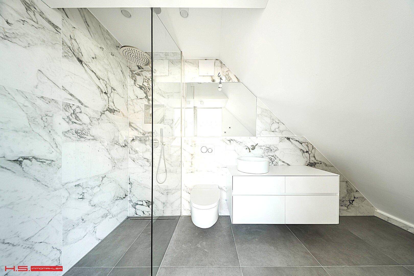 Modernes Badezimmer mit begehbarer Dusche, Marmorfliesen und schräger Decke.