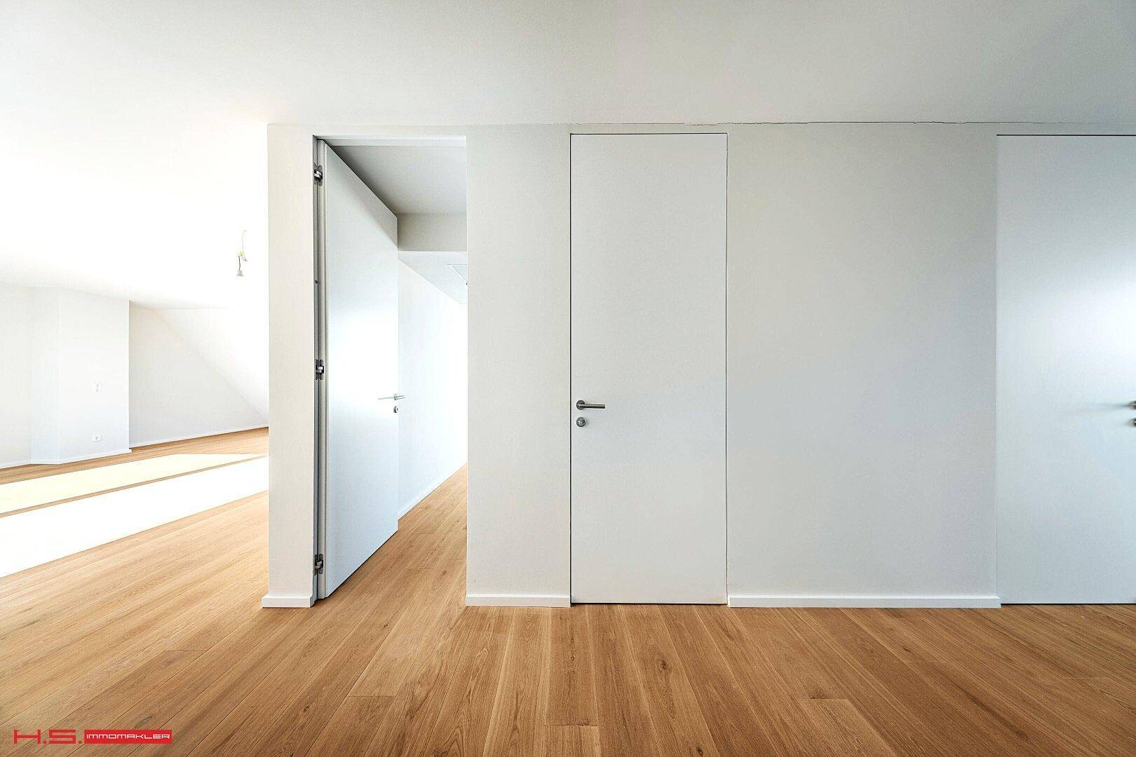 Moderner Flur mit Holzboden und minimalistischen, bündigen Türen.