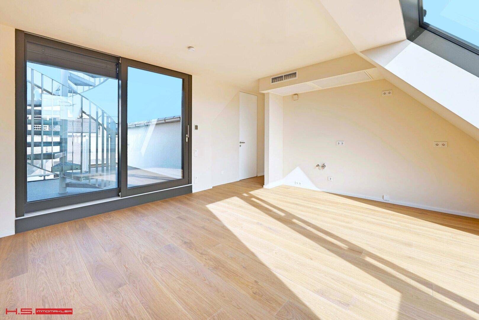 Heller Raum mit Holzboden und Zugang zur Dachterrasse über eine große Schiebetür.