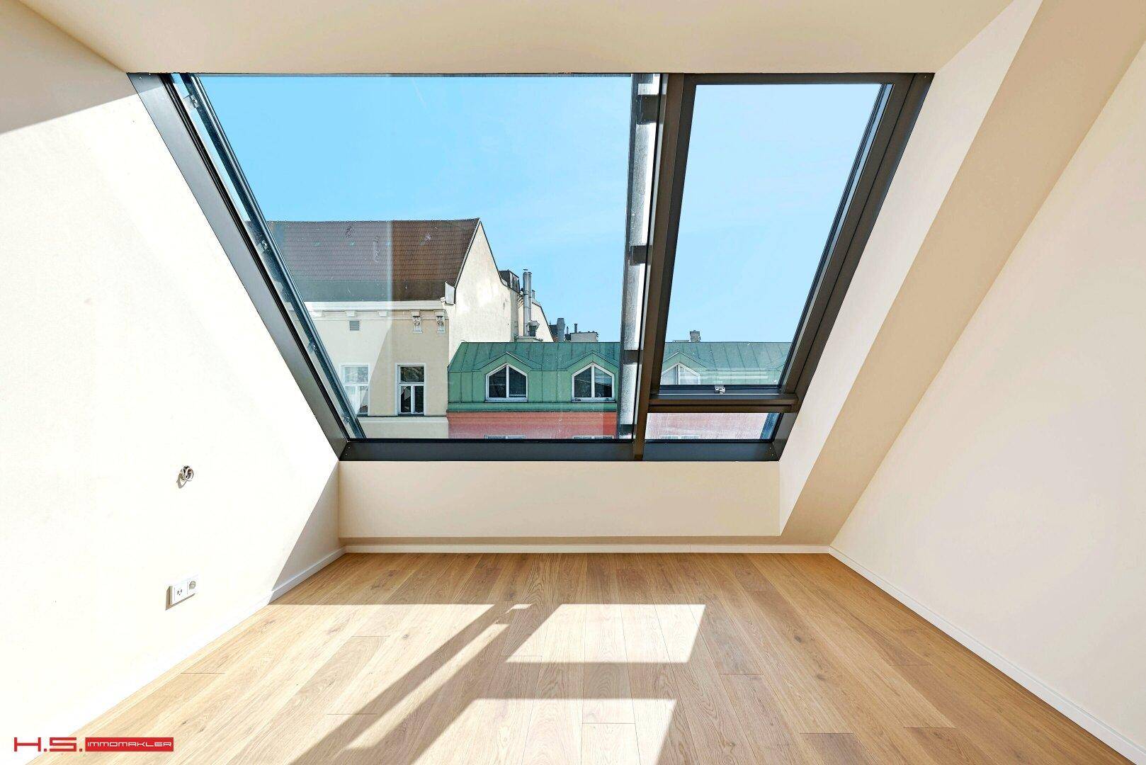 Heller Raum mit Holzboden und großem Dachfenster, bietet viel natürliches Licht und Ausblick.