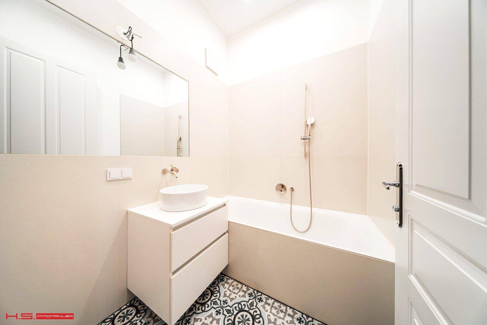 Modernes Badezimmer mit Badewanne, Einzelwaschbecken und gemusterten Fliesenboden.