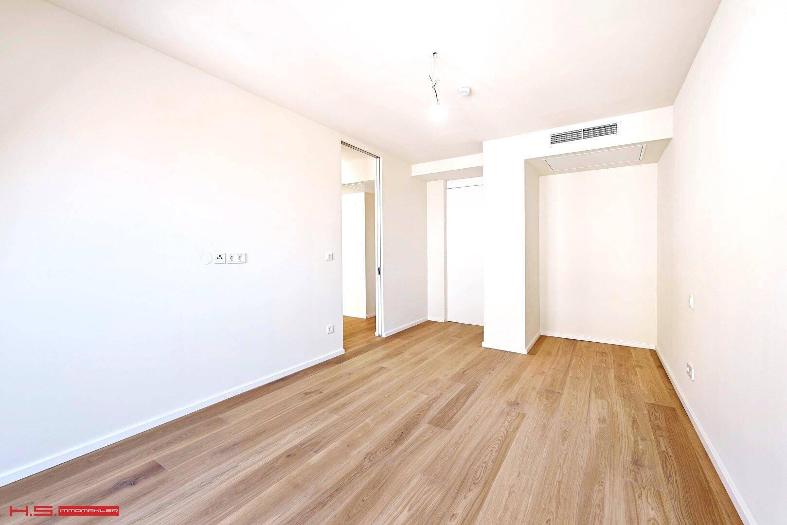 Geräumiges, helles Zimmer mit Parkettboden und moderner Lüftungsanlage, bereit zur Einrichtung.