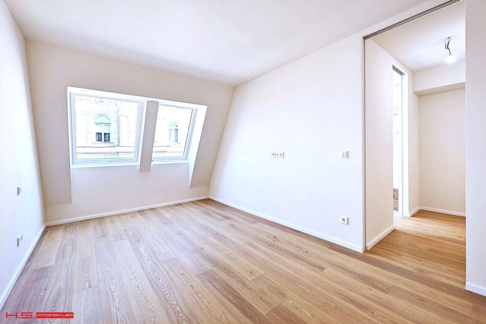 Helles Zimmer mit Dachschrägen, Parkettboden und großen Dachfenstern, ideal als Schlafzimmer.