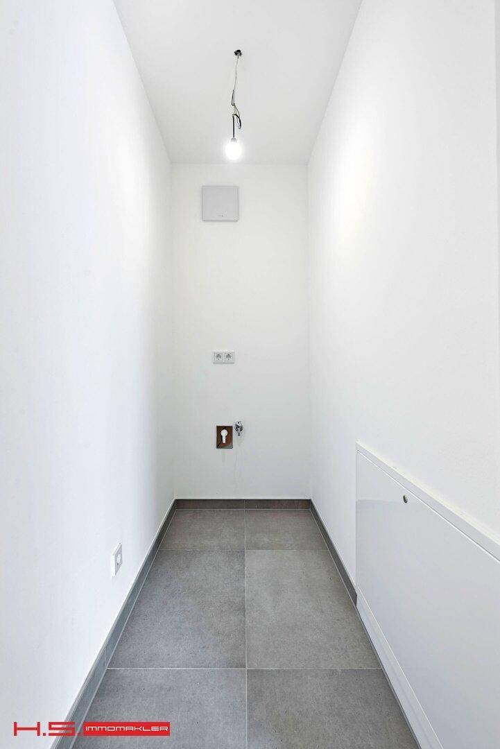 Schmaler Hauswirtschaftsraum mit Fliesenboden und Anschlüssen für Waschmaschine und Trockner.