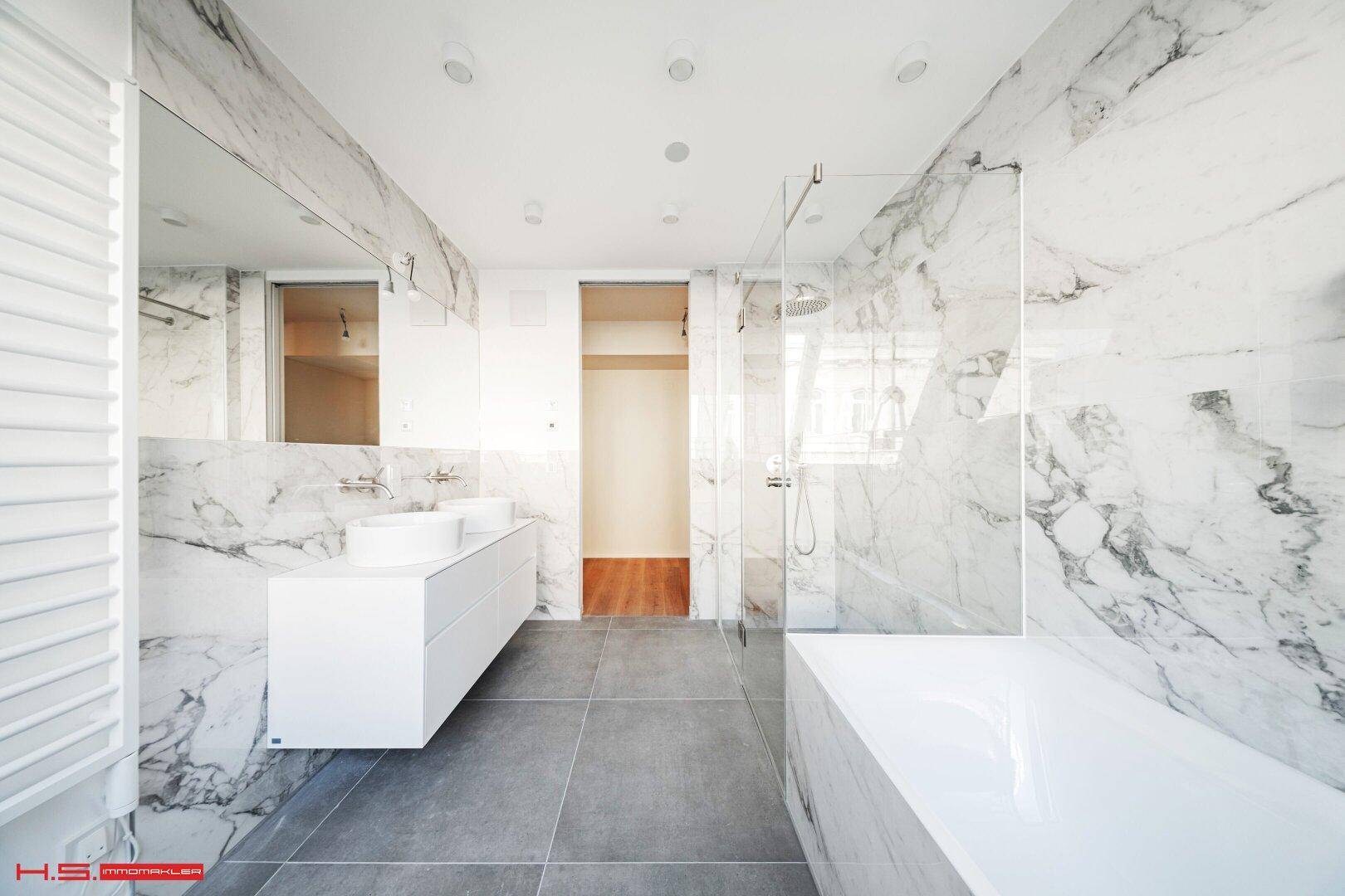 Luxuriöses Badezimmer mit Marmorfliesen, Doppelwaschbecken, Badewanne und begehbarer Dusche.