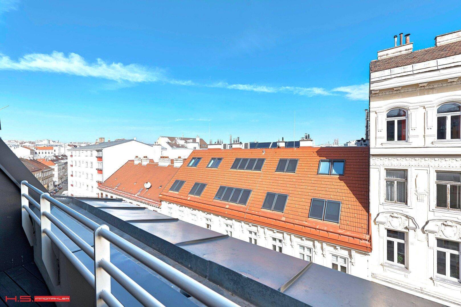 Weitläufiger Blick über die Dächer der Stadt mit traditionellen Ziegeldächern und Dachfenstern.