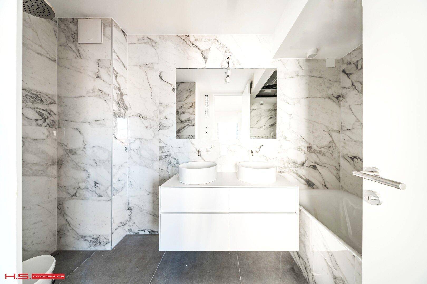 Luxuriöses Badezimmer mit Marmorfliesen, Doppelwaschbecken und moderner Ausstattung.