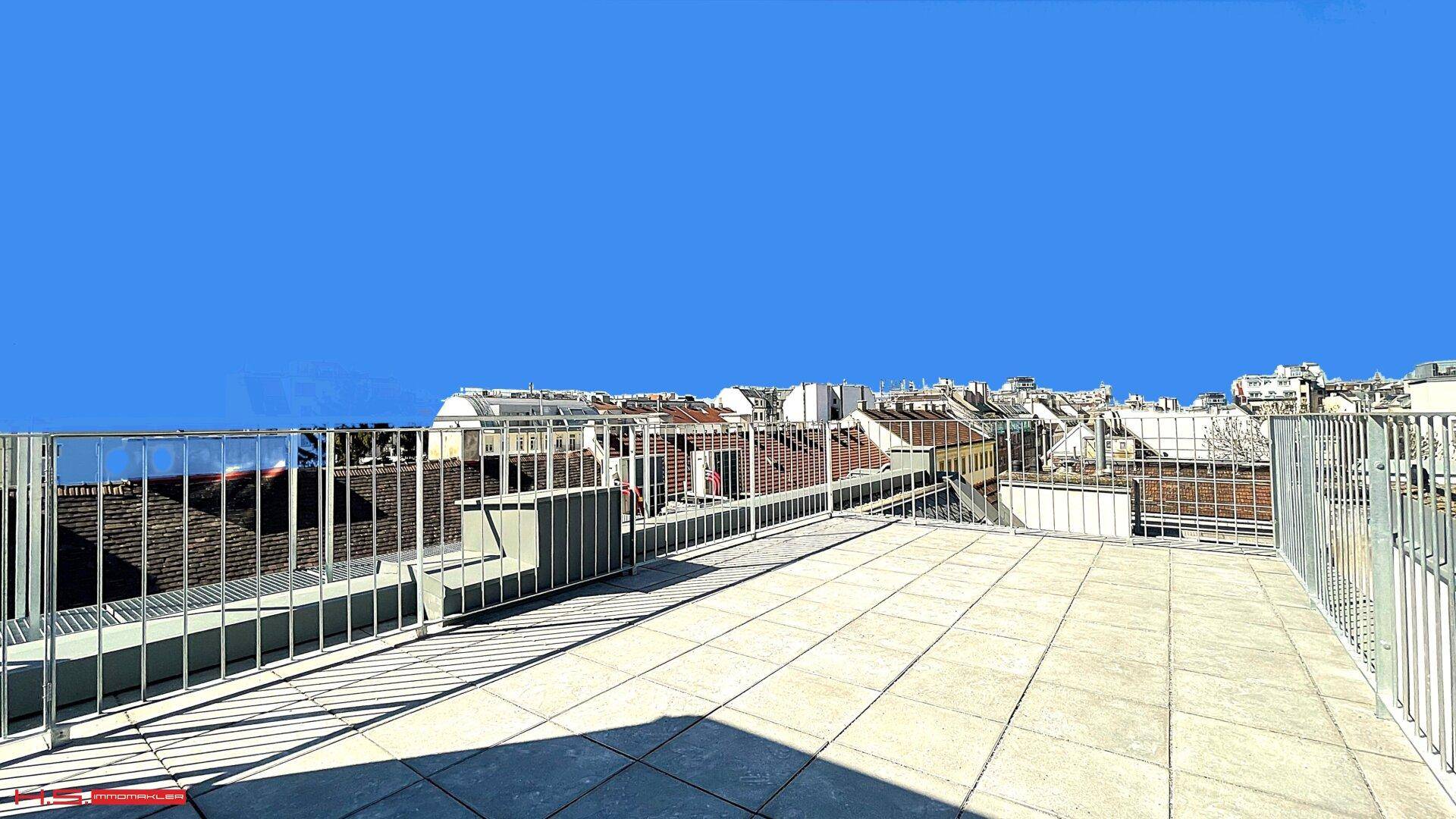 Weitläufige Dachterrasse mit Fliesenboden und Panoramablick über die Stadt.