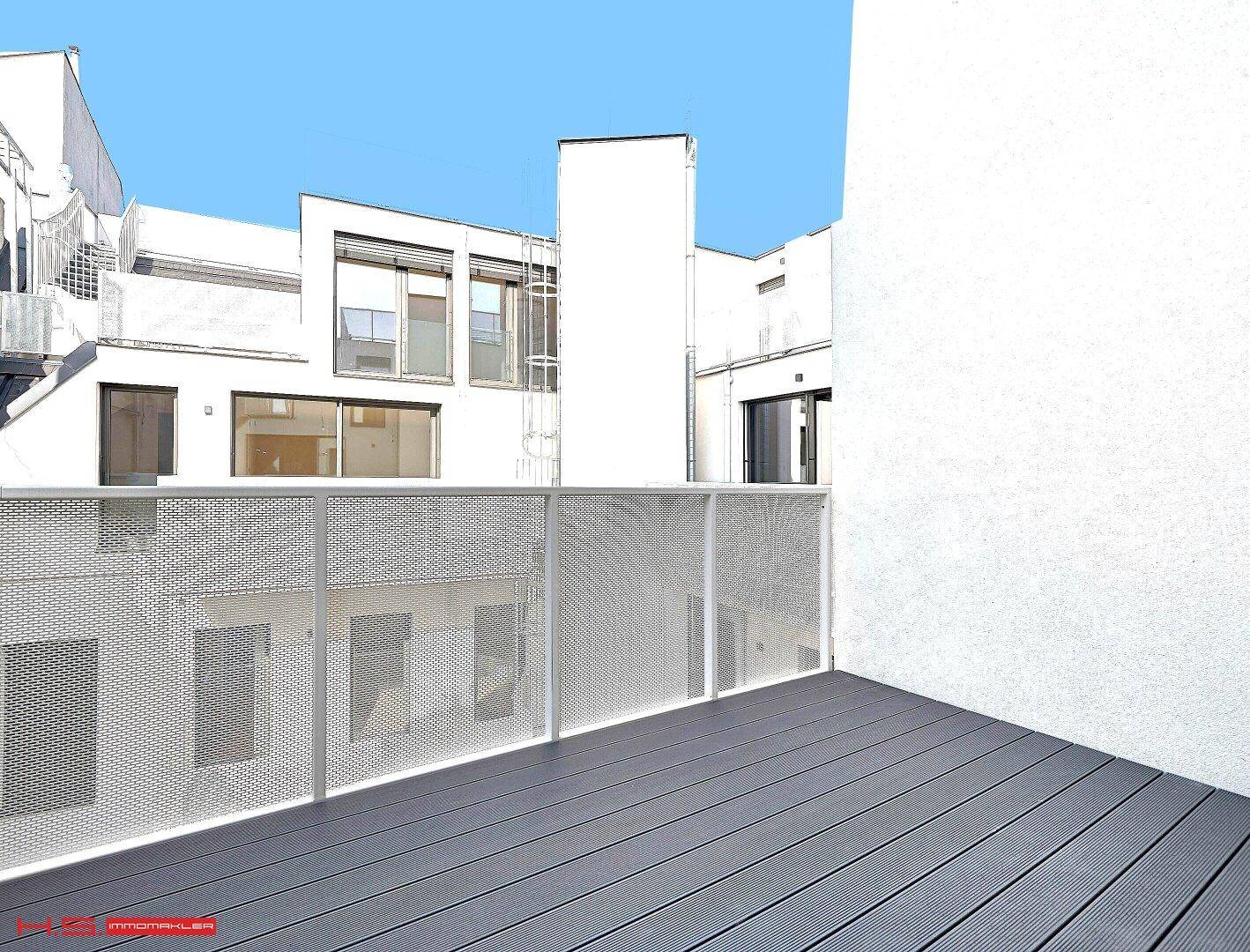 Leere Terrasse mit modernen Bodenbelägen und Metallgeländer, umgeben von Gebäuden.