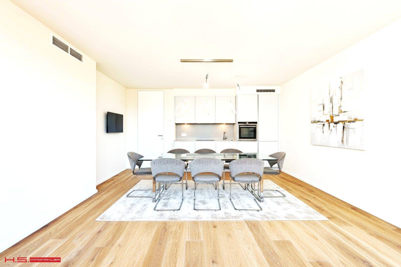 Moderner Essbereich mit Holzboden und integrierter Küchenzeile in minimalistischem Design.