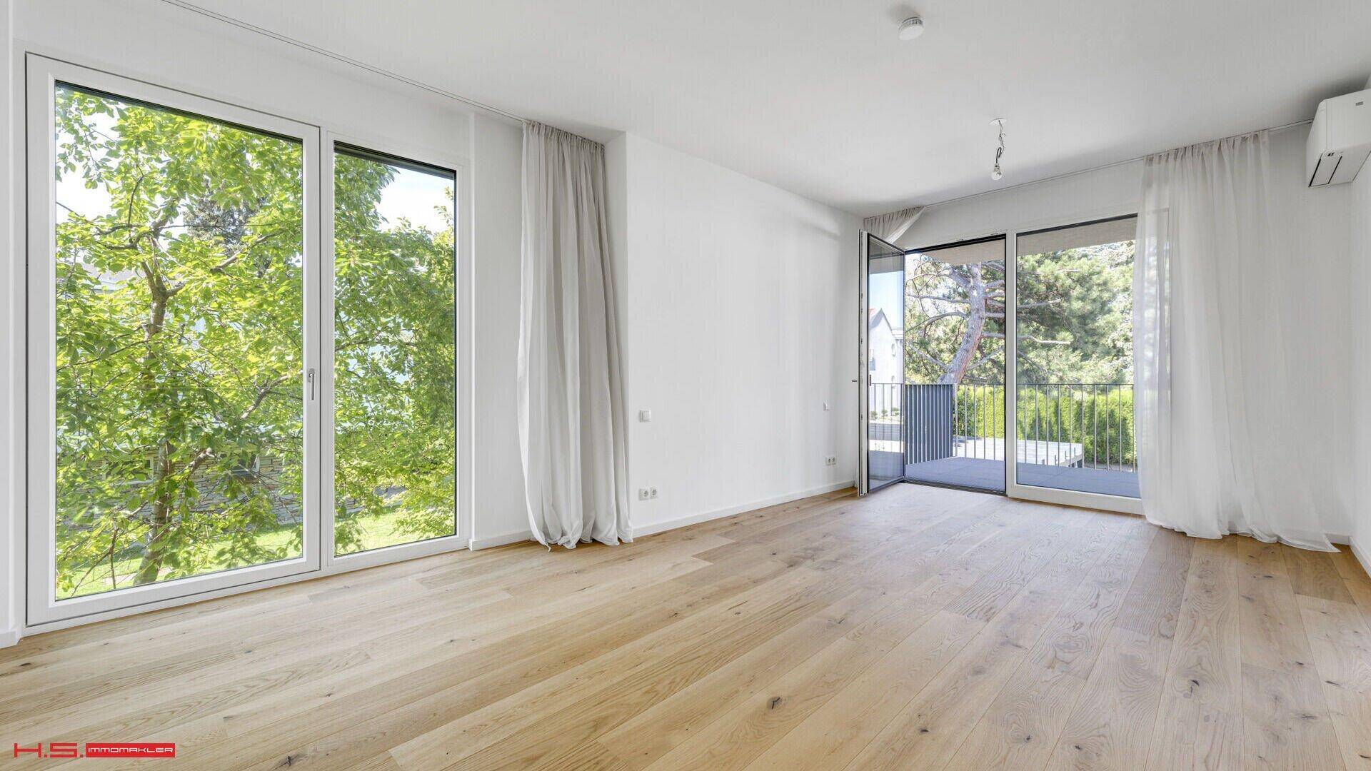 Geräumiger Wohnbereich mit Eichenparkett, großen Fenstern und direktem Zugang zum Balkon.
