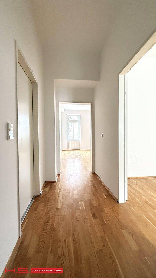 Heller Flur mit Parkettboden, der zu weiteren Zimmern führt und viel Tageslicht bietet.