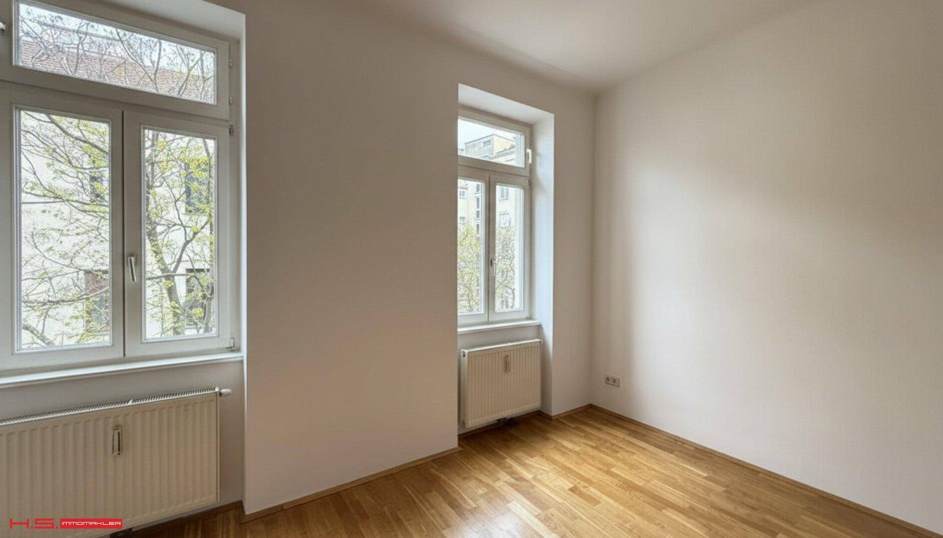 Helles Zimmer mit Parkettboden und zwei Fenstern, ideal als Schlaf- oder Arbeitszimmer nutzbar.