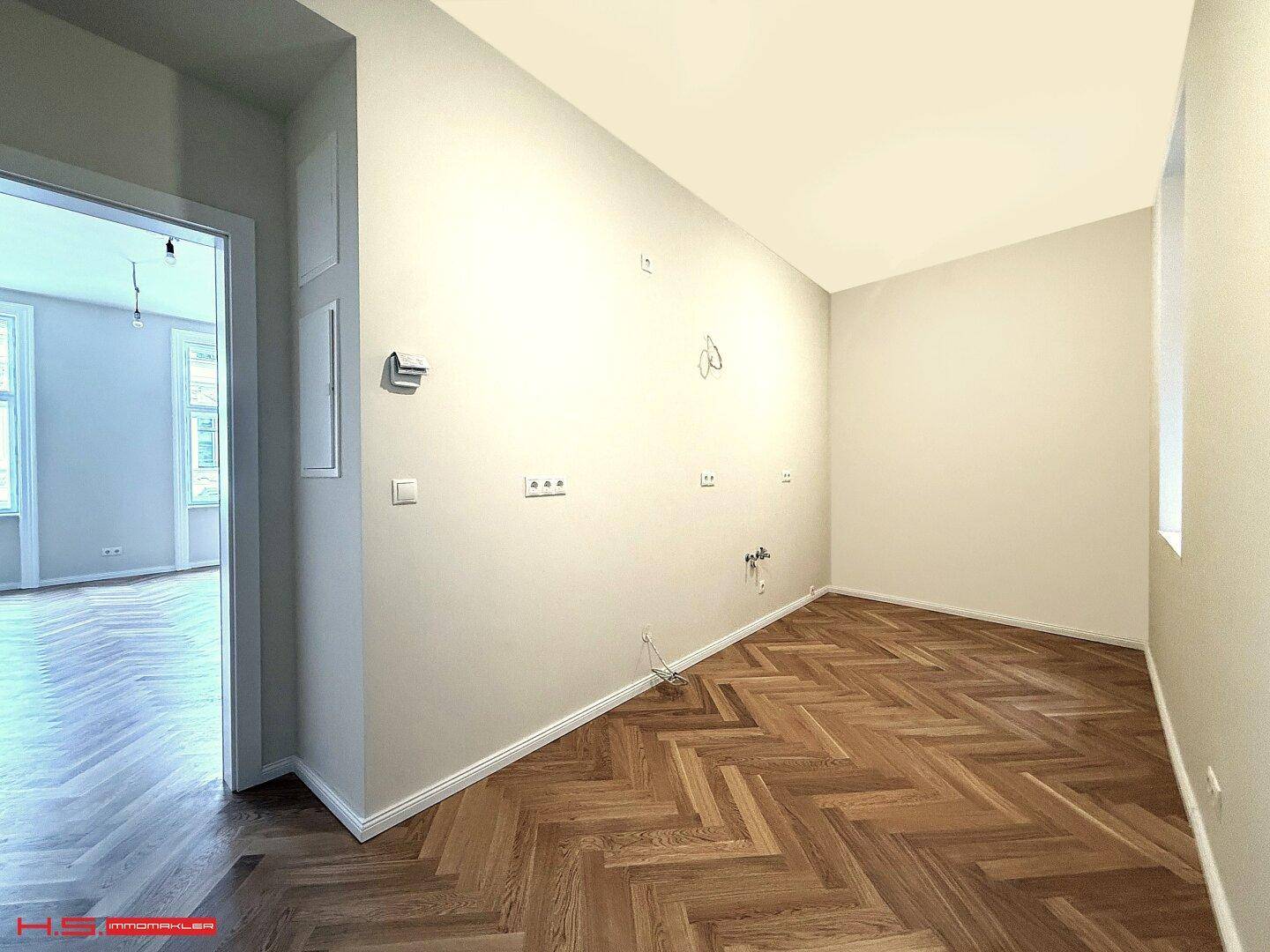 Heller Flur mit Fischgrätparkett, der zu weiteren Räumen der Wohnung führt.
