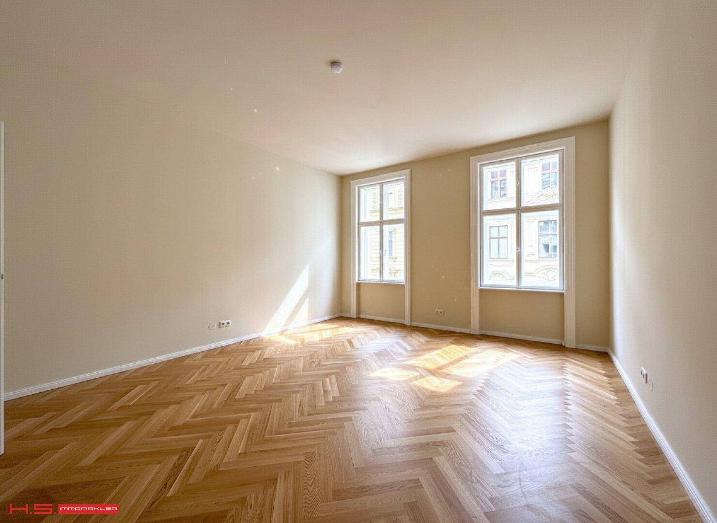 Sonniges Wohnzimmer mit Fischgrätparkett und viel Tageslicht, das durch die Fenster fällt.