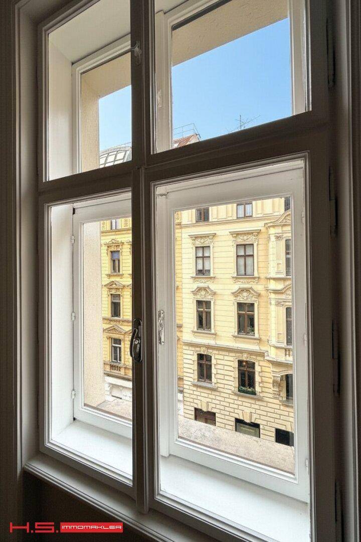 Blick aus dem Fenster auf die gegenüberliegende historische Gebäudefassade mit vielen Details.
