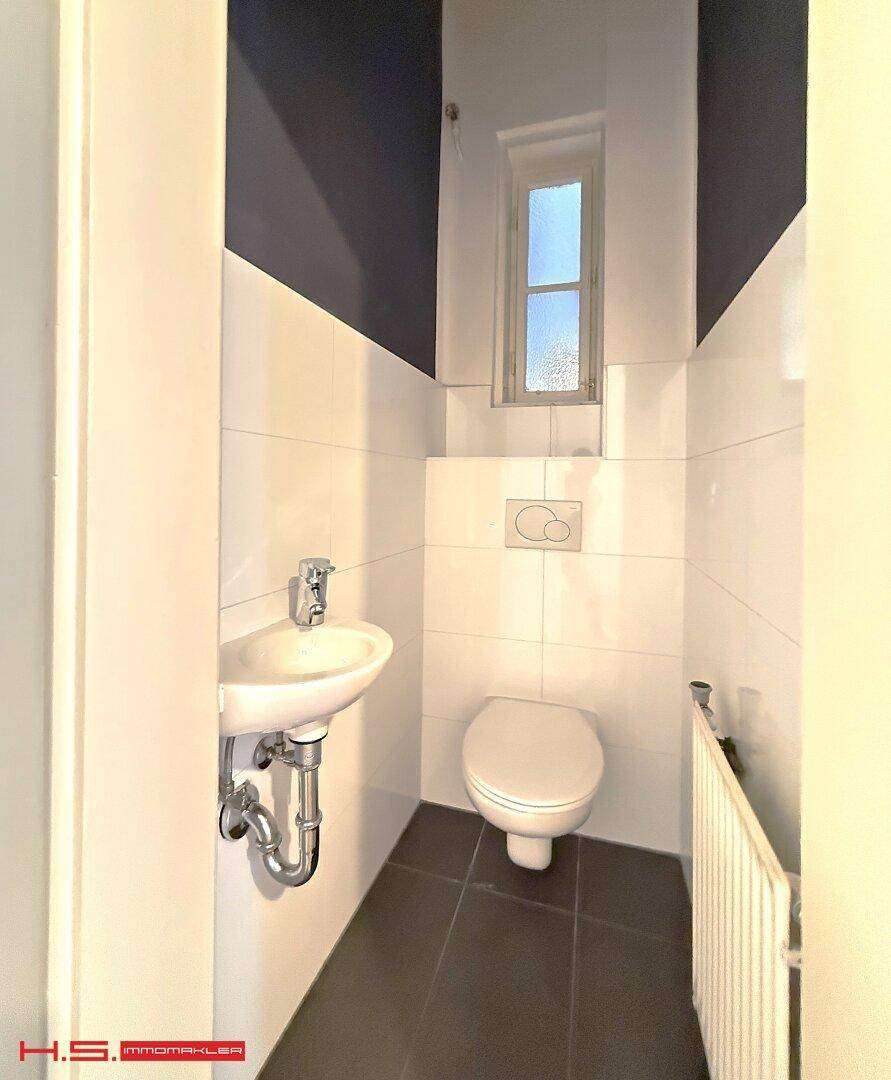 Kleines Gäste-WC mit Fenster, wandhängendem WC und Waschbecken.