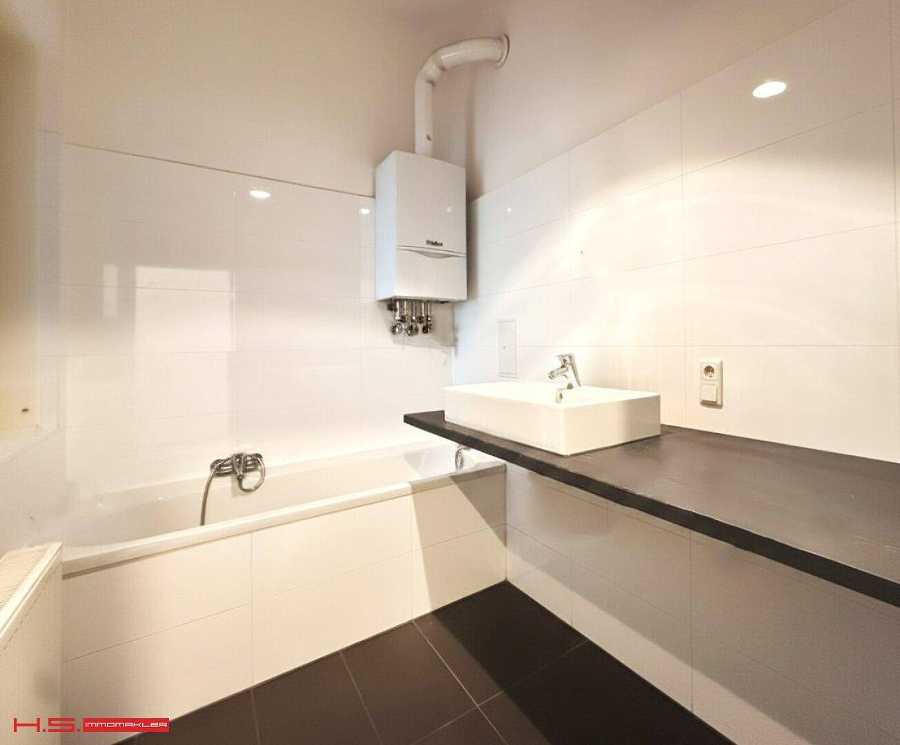 Modernes Badezimmer mit Badewanne, Waschbecken und Gastherme an der Wand.