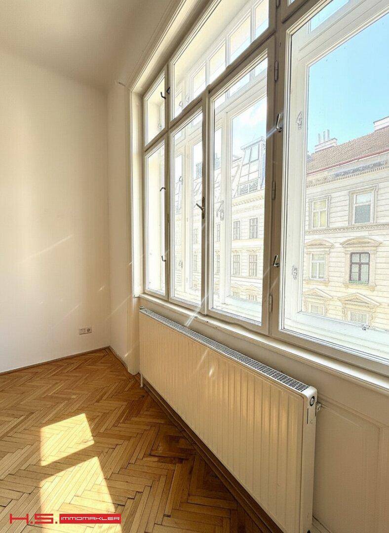 Großes Fenster mit Blick auf die umliegenden Gebäude und Heizkörper darunter.