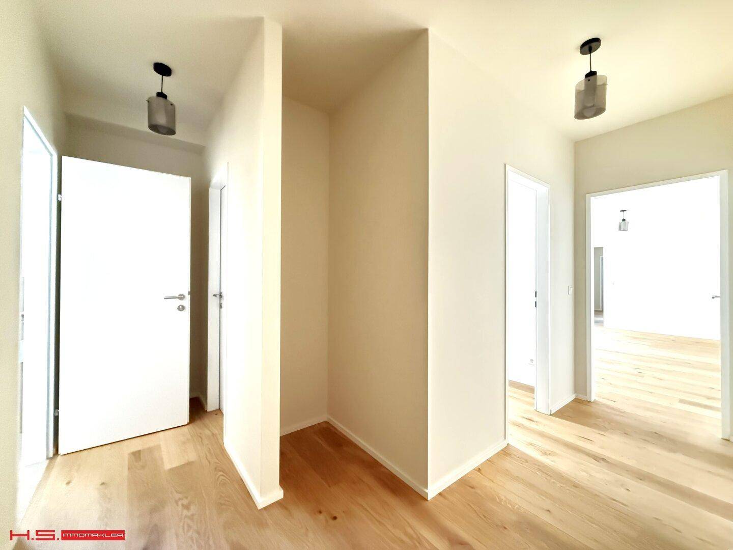 Heller Flur mit Holzboden und mehreren Türen, der verschiedene Räume verbindet.