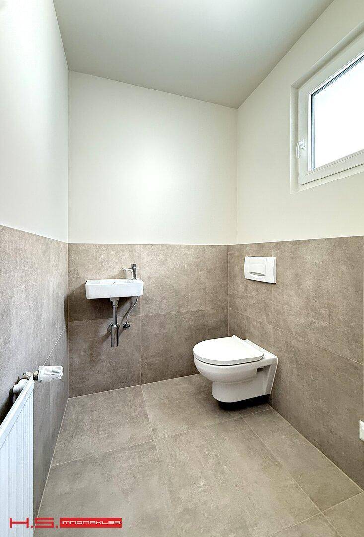 Modernes Gäste-WC mit Wand-WC, kleinem Waschbecken und Fenster.