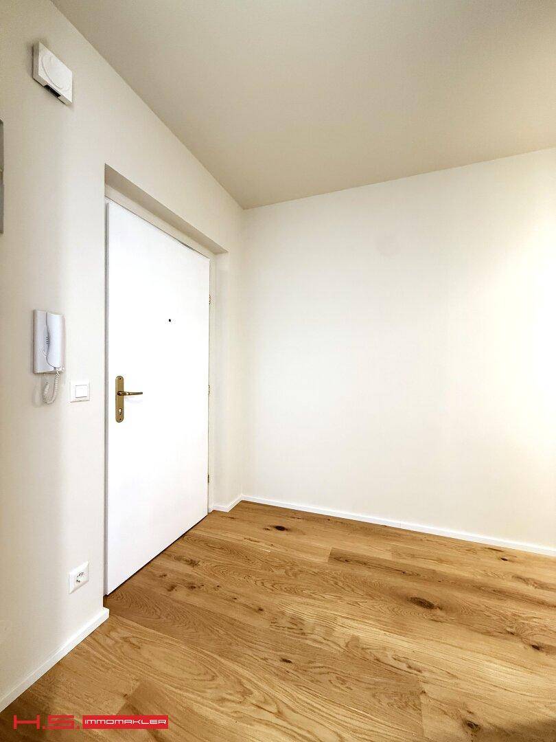 Eingangsbereich mit Holzboden und Gegensprechanlage, hell und funktional gestaltet.