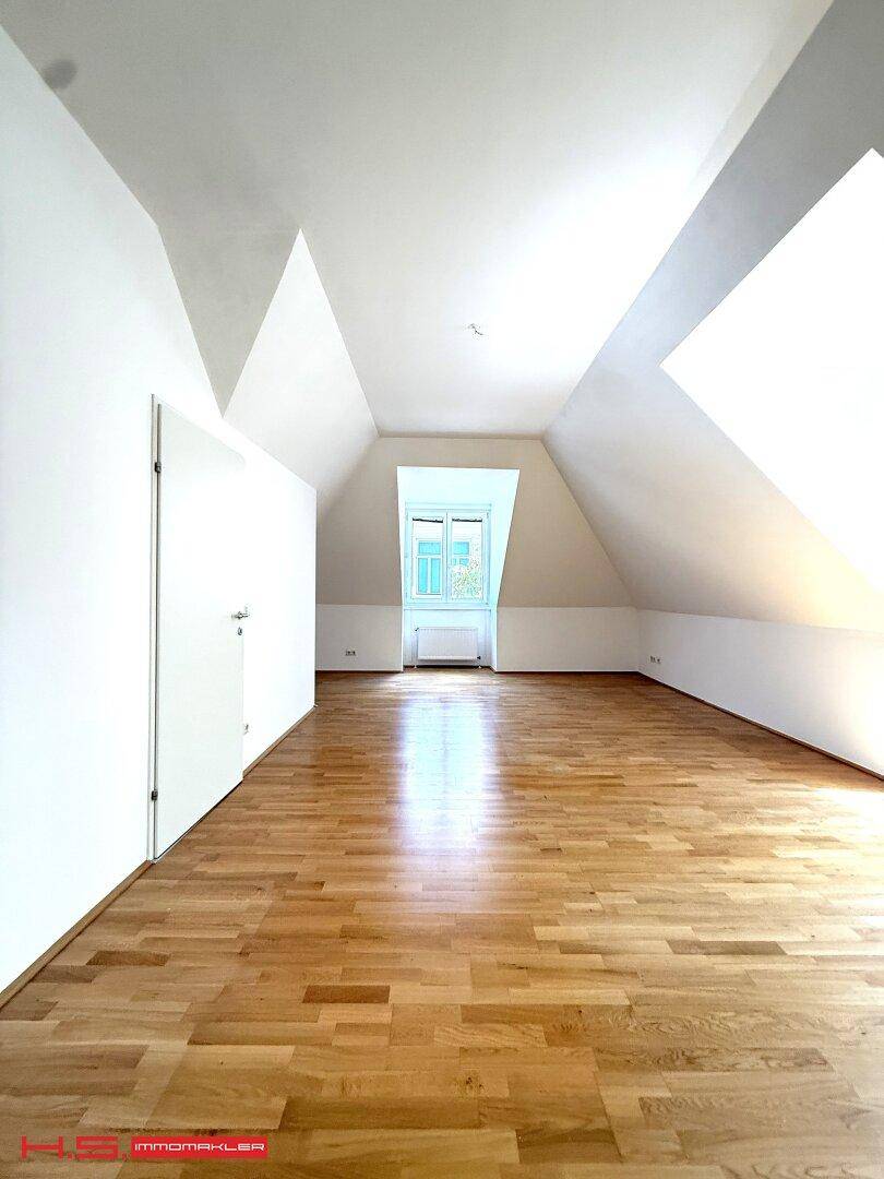 Geräumiger, leerer Dachgeschossraum mit Holzboden und schrägen Wänden, bietet vielseitige Gestaltungsmöglichkeiten.