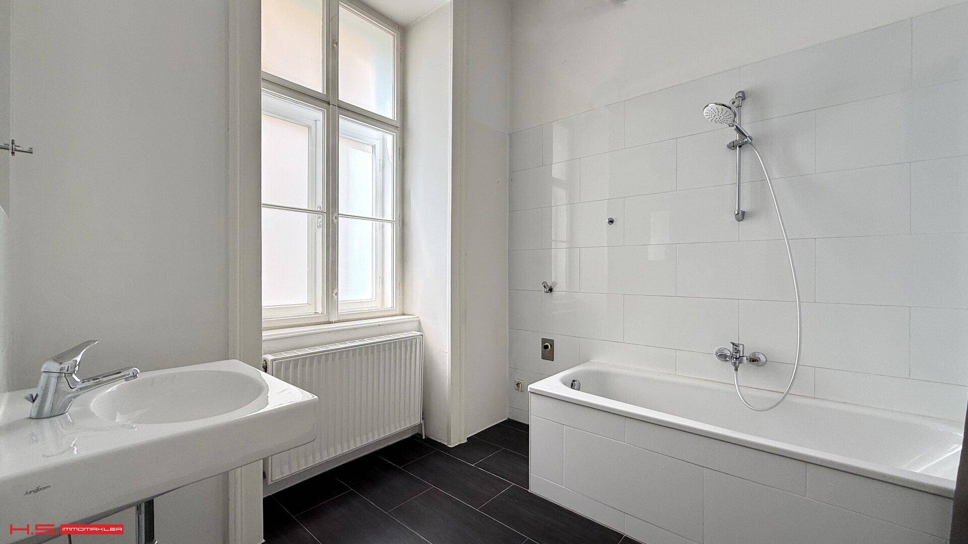 Modernes Badezimmer mit weiß gefliesten Wänden, Badewanne und Fenster für Tageslicht.