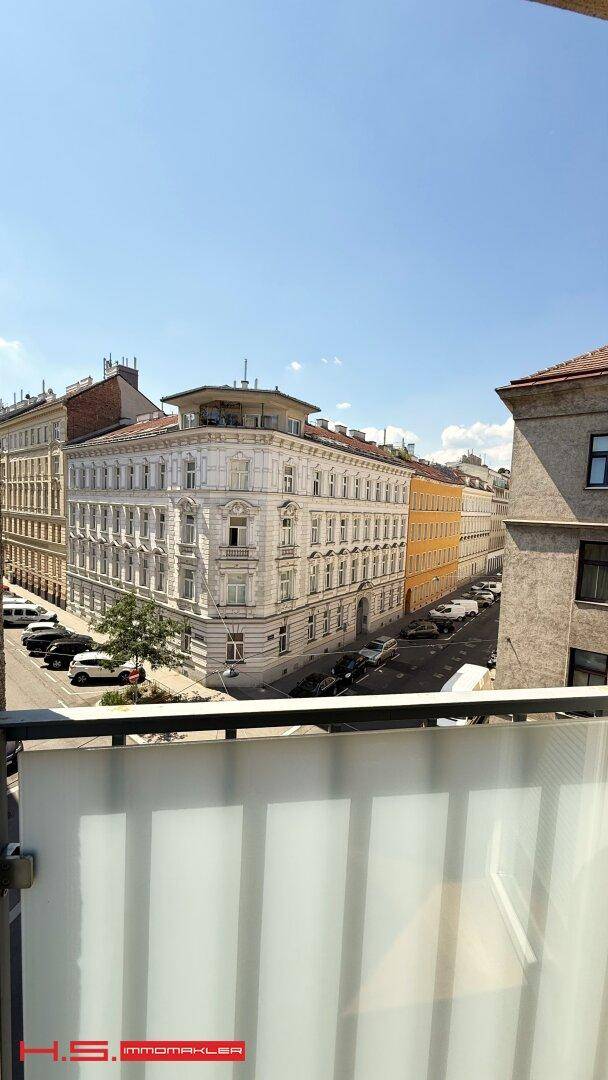 Ausblick von einem Balkon auf eine belebte Straße mit historischen Gebäuden und Stadtansicht.
