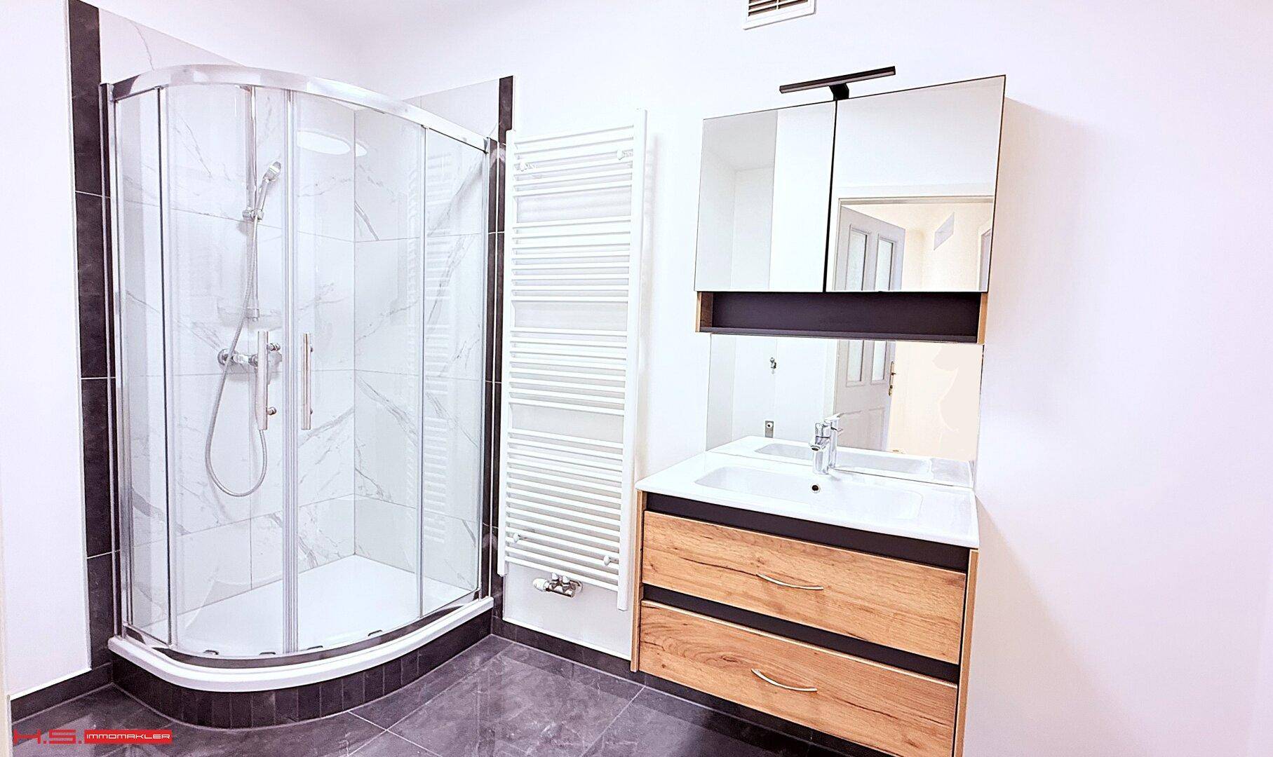 Modernes Badezimmer mit Eckduschkabine, Holzwaschtisch und beheiztem Handtuchhalter.