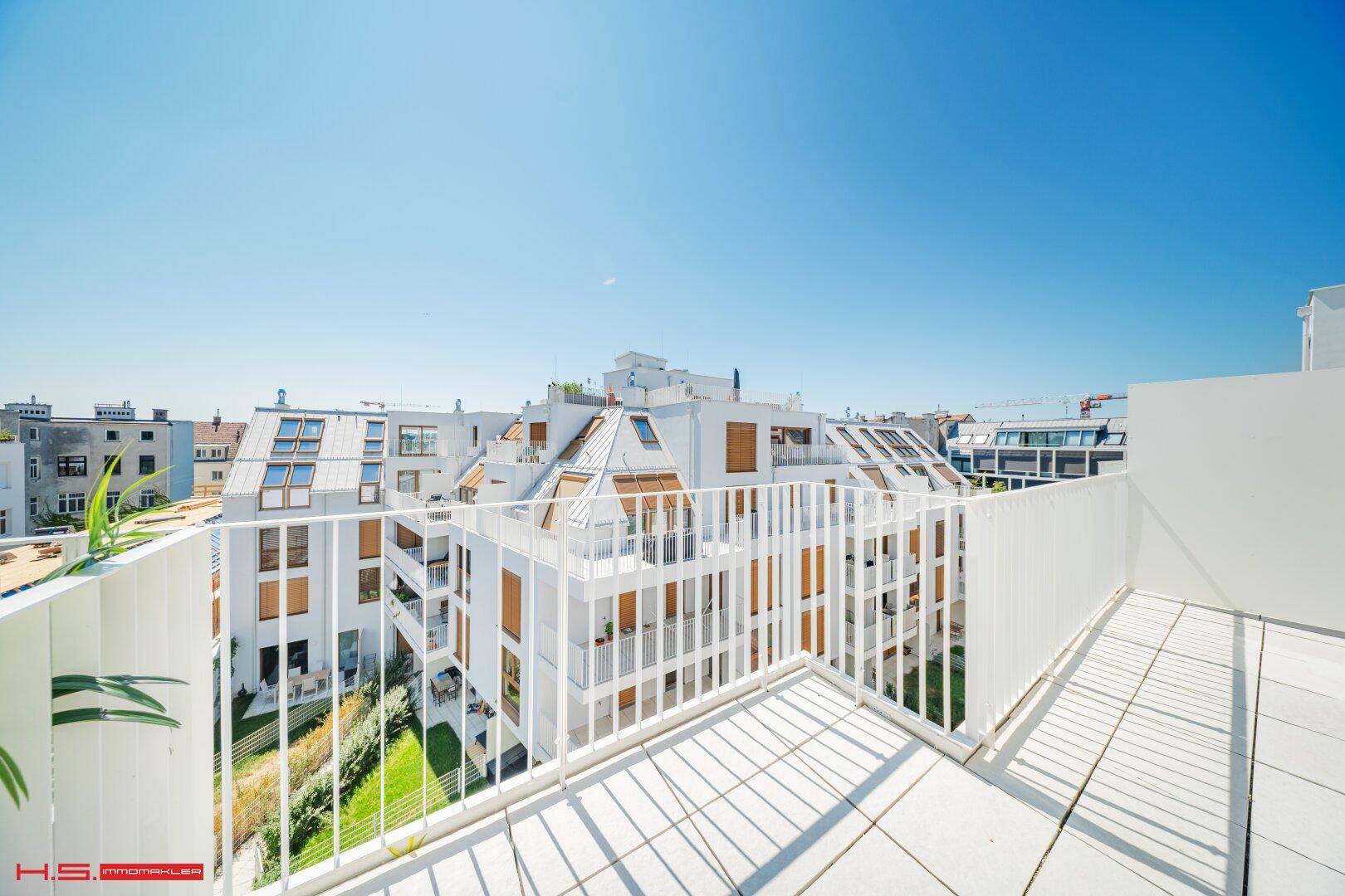 Dachterrasse mit Blick auf moderne Wohngebäude und grüne Innenhöfe, bietet viel Sonnenlicht.