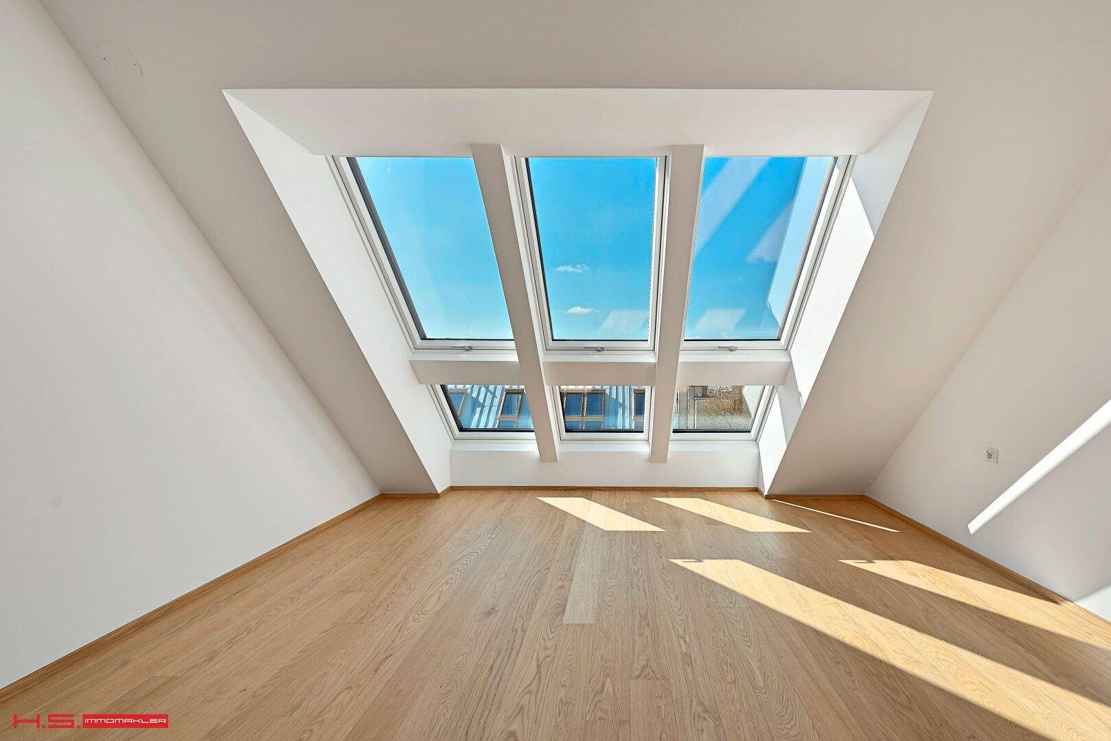 Geräumiger Wohnbereich im Dachgeschoss mit beeindruckenden Dachfenstern für viel Tageslicht.