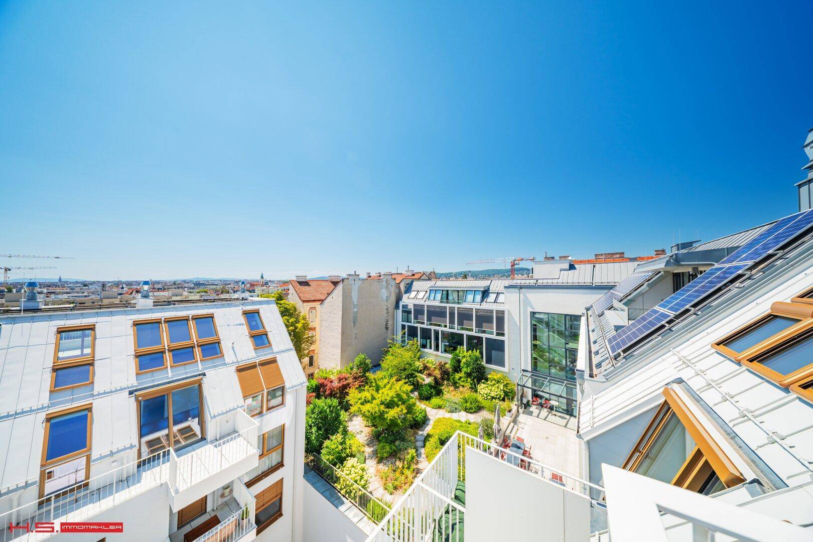 Dachlandschaft eines modernen Wohnkomplexes mit Solarpaneelen und begrünten Innenhöfen.