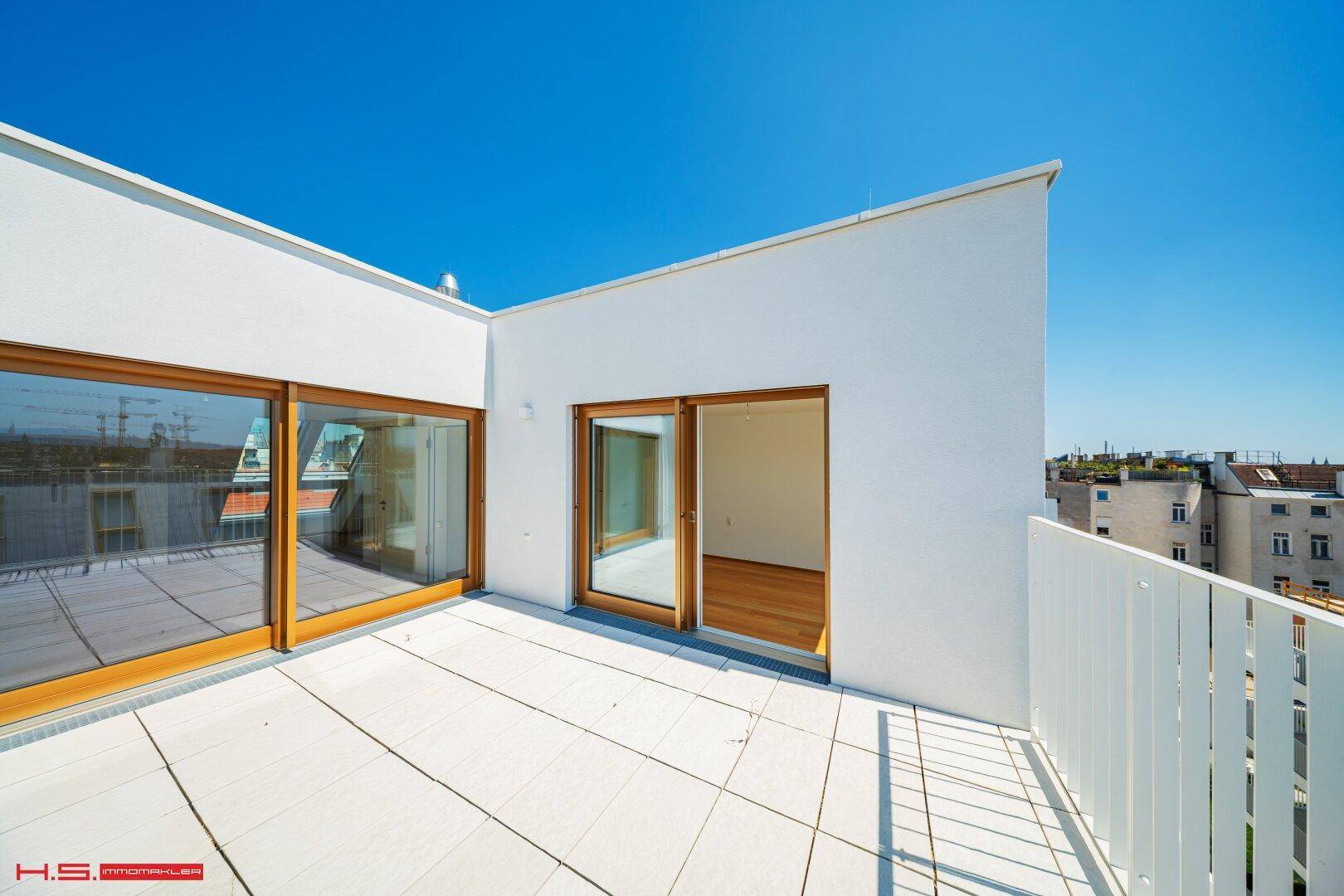 Sonnige Dachterrasse mit weißem Geländer und Zugang zu Innenräumen, ideal für Entspannung im Freien.