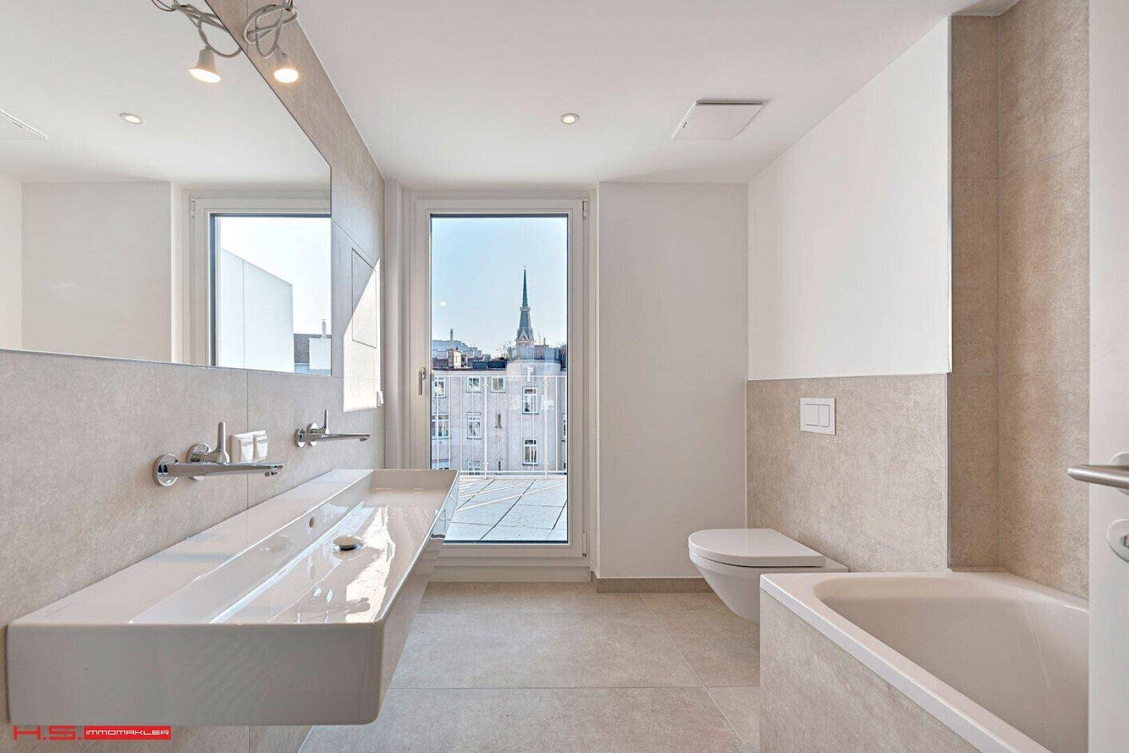 Modernes Badezimmer mit Doppelwaschbecken, Badewanne, Wand-WC und Zugang zu einem Außenbereich.
