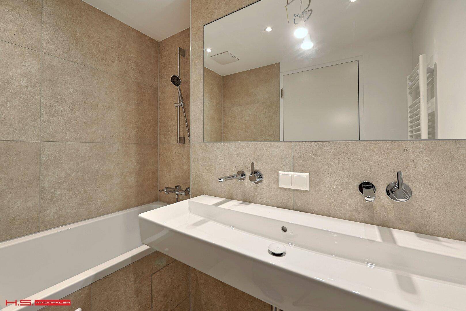 Modernes Badezimmer mit Badewanne, integrierter Dusche und großem Spiegel über dem Waschbecken.
