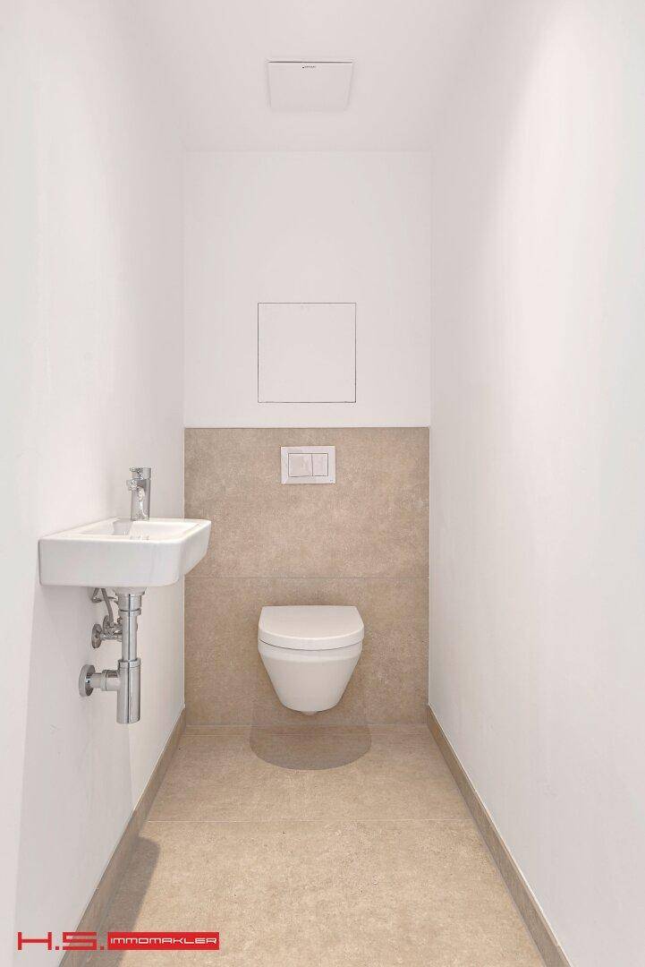 Kleines Gäste-WC mit Wand-WC und modernem Waschbecken in minimalistischem Design.