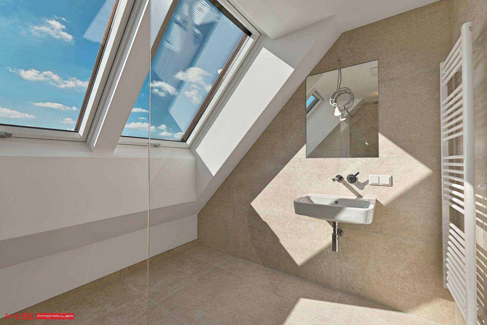 Modernes Badezimmer mit Dachfenster, Waschbecken und beheiztem Handtuchhalter.