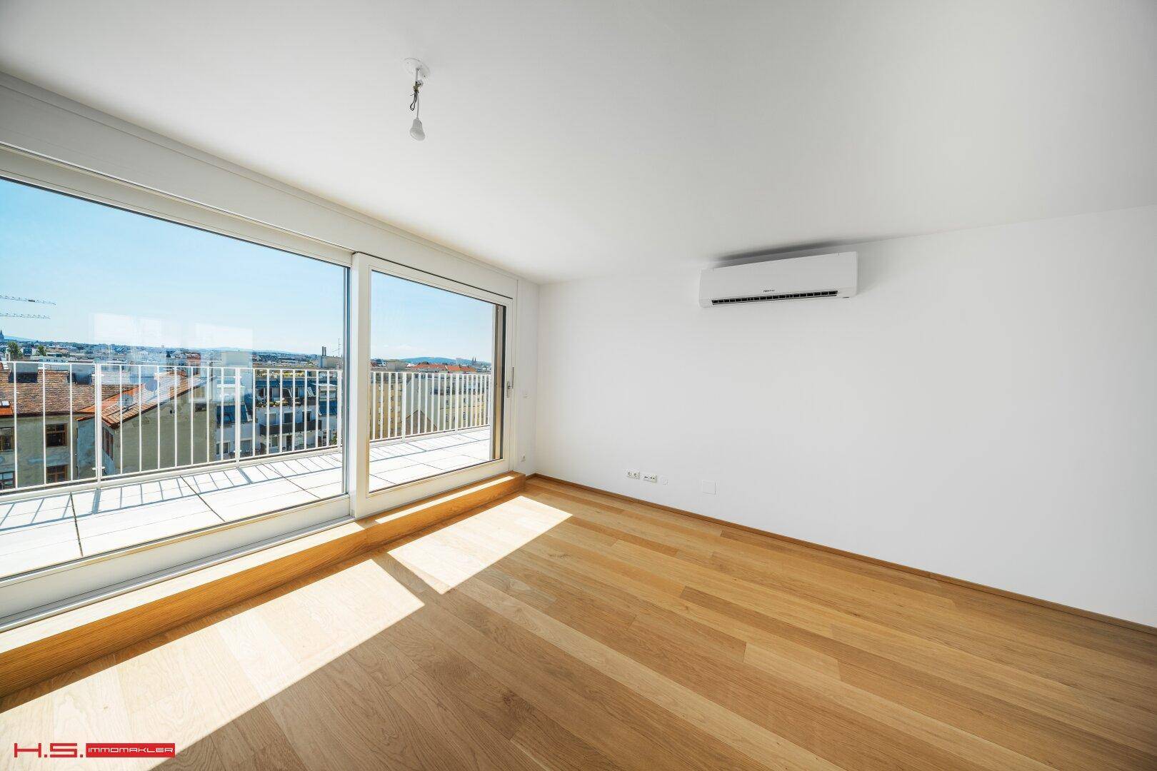 Helles Wohnzimmer mit Holzboden, großen Schiebetüren und Zugang zur Terrasse.