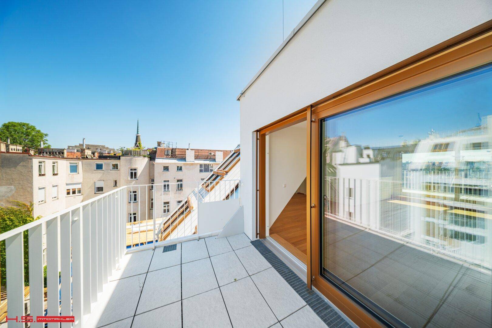 Sonnige Terrasse mit Stadtblick und Zugang zu einem hellen Innenraum.