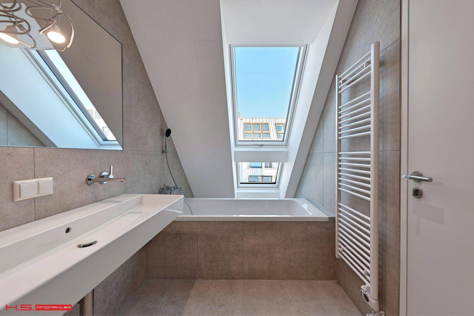 Modernes Badezimmer mit Badewanne, schrägen Wänden, Dachfenster und beheiztem Handtuchhalter.