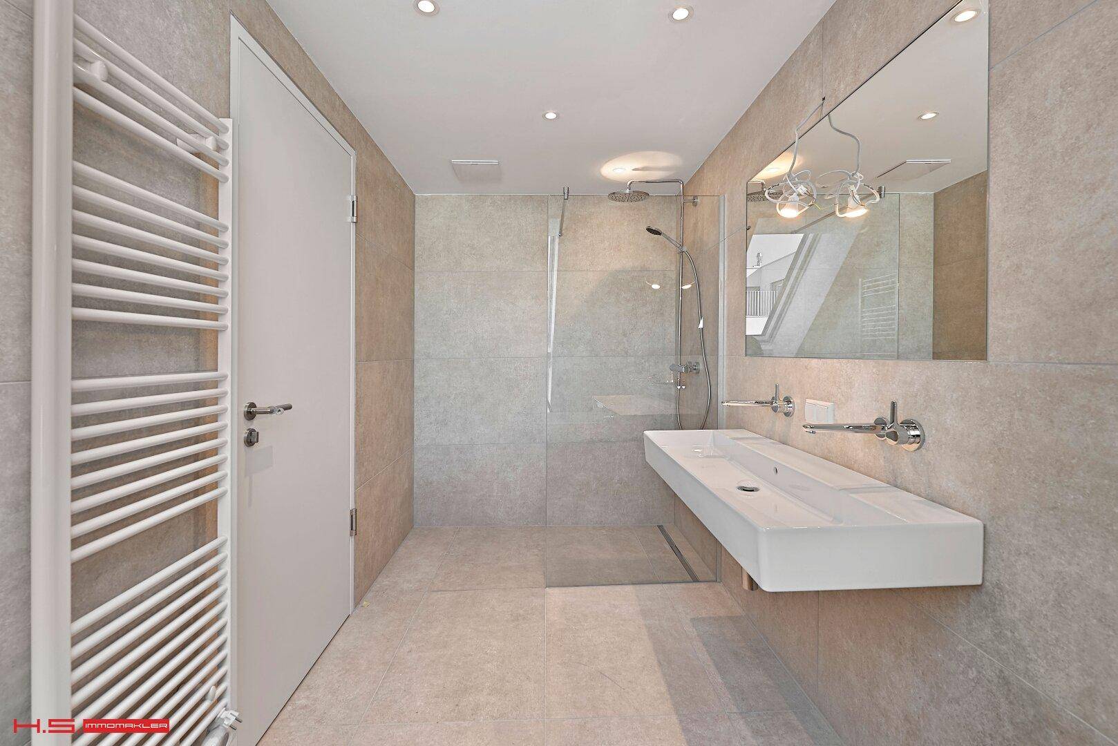 Elegantes Badezimmer mit großer Dusche, Doppelwaschbecken und beheiztem Handtuchhalter.